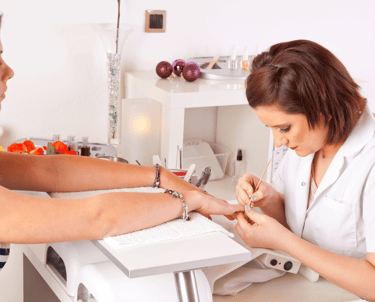 Nageldesigner mach Nägel einer Kundin