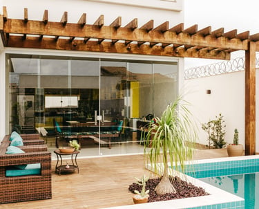 Modern backyard patio with a wooden pergola, swimming pool, and wicker lounge chairs.