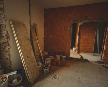 Interior room under construction with red brick walls, concrete floors, and building materials.