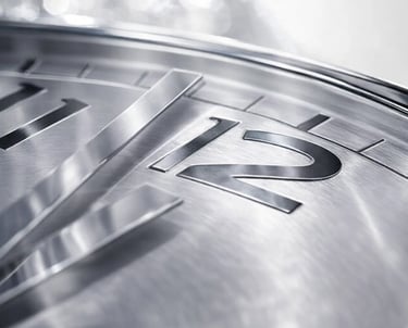 Close-up of a silver luxury watch face with brushed metal texture and 12 o'clock numeral.