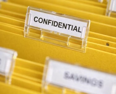 Yellow hanging file folders in an office drawer with a confidential label for secure document storage.