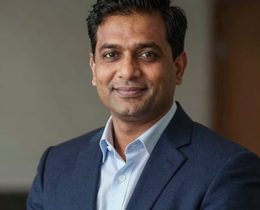 A professional corporate headshot of a South Asian male real estate expert in his 40s, sharp navy blazer, confident and trustworthy expression, premium lighting.