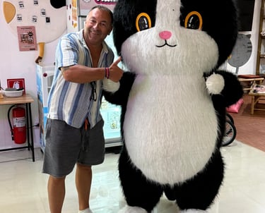 Guest posing with CatWorld cat mascot inside Samui cat cafe