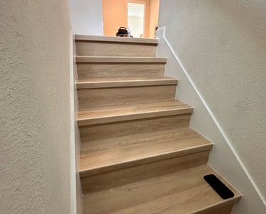 Modern staircase renovation with hardwood treads, black metal railings, and open risers in a Kissimm