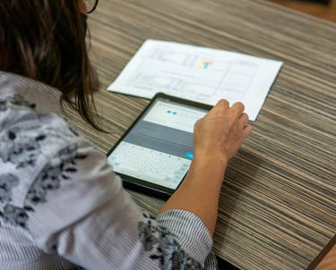a woman sitting at a table with a tablet computer