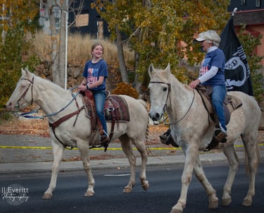 a young woman and older woman riding horses down a street