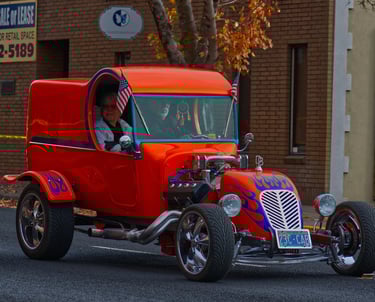a orange hot rodder car with a man and a woman