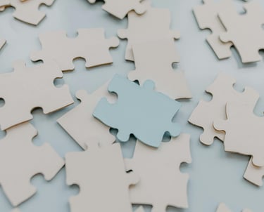 Witte puzzelstukjes met één blauw stuk als metafoor voor sturen en verbinden in moreel beraad.