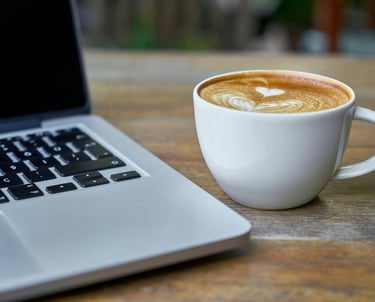 Laptop en cappuccino voor een online kennismakingsgesprek van schoolleider met Praktisch Met Lef.