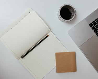 Werkplek van schoolleider met laptop, koffie en notitieboekje voor korte morele reflectie