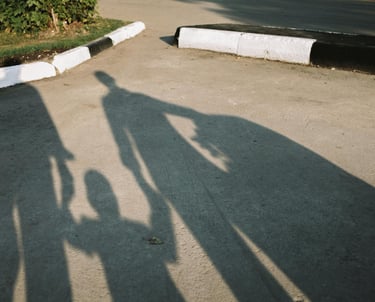 Schaduwen van mensen met een kind centraal, symboliseert perspectief en relationele verbinding.