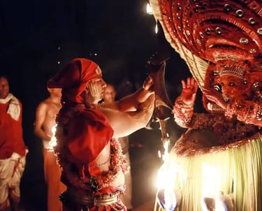 Person performing Theyyam ritual in Kerala, adorned in traditional attire.