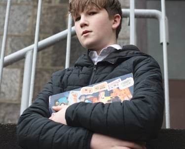 Film production: a boy in a black jacket holding a book