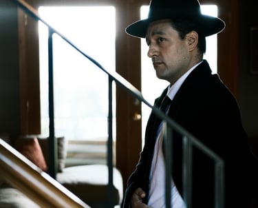 Production company shot of an actor in a suit and hat