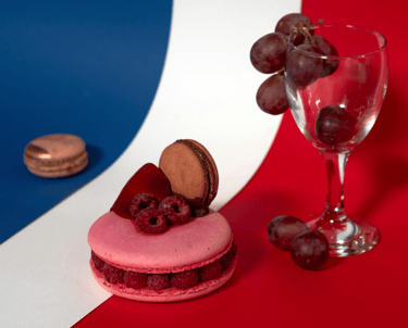 a macarons dessert with a glass of wine and grapes on a French flag