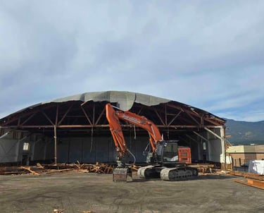 excavator in front of an demolition project of an arena