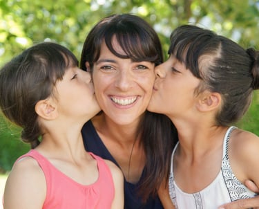 photo de famille avec deux filles embrassant leur mère.