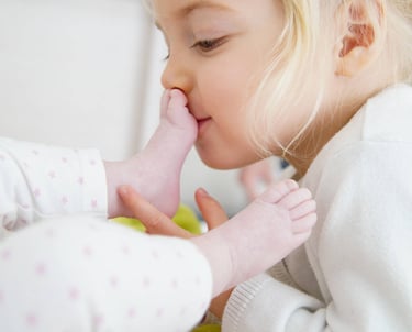 un enfant fais un bisou sur le pied d'un bébé lors d'une séance photo