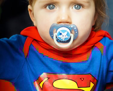 Bébé avec un pyjama Superman, sucette et yeux bleus. Super héro naissance.