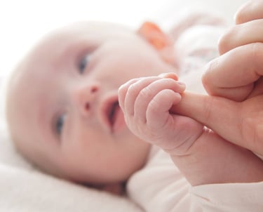 Gros plan sur la main de bébé serrant le doigt de sa mère. Portrait doux de nouveau né.