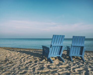 two beach chairs facing the water