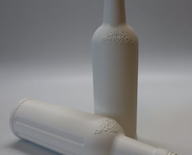 Du balti 3D spausdinti butelių prototipai iš PLA plastiko, stovintys ant balto pagrindo