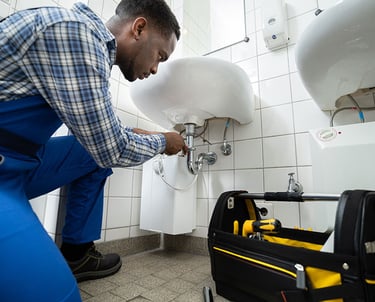 Handyman fixing a plumbing leak under the sink in a London home