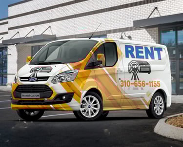 A colorful rental van with advertising graphics parked outside a building.