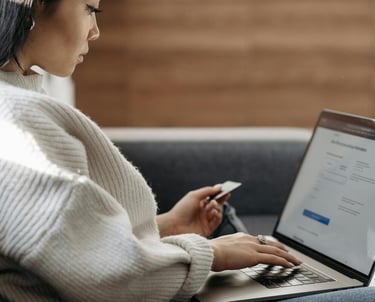 photographie d'une femme qui regarde son ordinateur portable avec une carte de crédit dans une main 