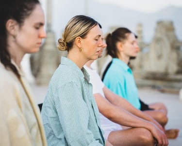Group of four women meditating in cross-legged position, with their eyes closed