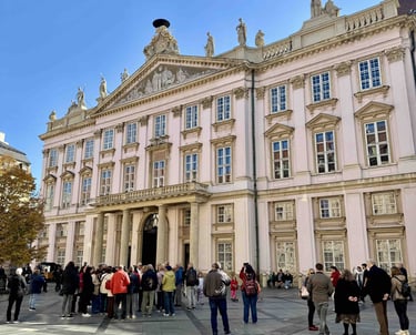 Fachada del Palacio Primacial de Bratislava en un día soleado, con un grupo de turistas reunidos en 