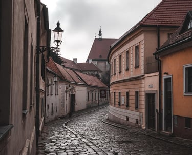 Calle adoquinada y estrecha del casco antiguo de Bratislava, con fachadas de casas de colores suaves