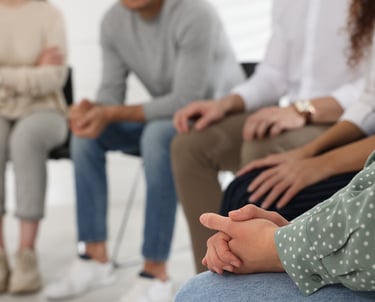 a group of people sitting in a circle with their hands clasped together