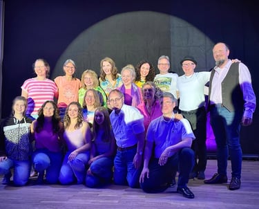 ein Gruppenfoto von knapp 20 freudigen Personen auf einer Bühne im Spotlight