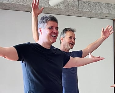 zwei strahlende Männer, die mit geöffneten Armen singen