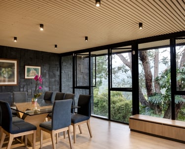 Interior moderno con ventanales de piso a techo y vista al jardín, iluminación cálida