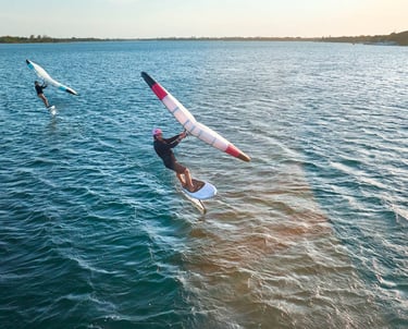 Saulėlydis Svencelėje su wing foil sportininku virš vandens paviršiaus