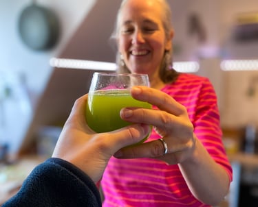 2 Hände reichen sich ein Glas Selleriesaft