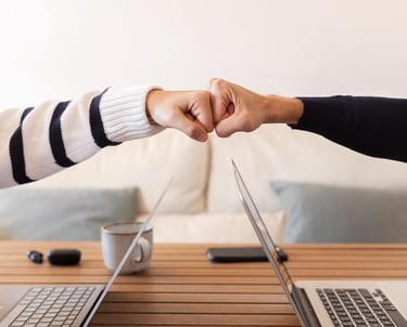 two people shaking hands over a laptop