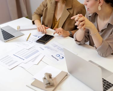 two women sitting at a table with papers and papers