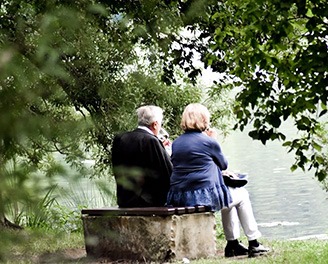 senior couple on a bench in front of lake having lunch