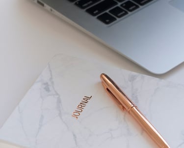 Un carnet, un stylo rose gold déposé sur un bureau attendre patiemment les notes inspirantes