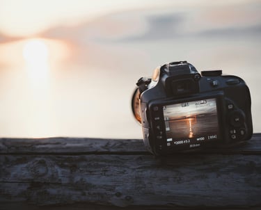 un appareil photo déposé sur une table de bois et positionné pour attendre le plus beau couché de soleil du lac