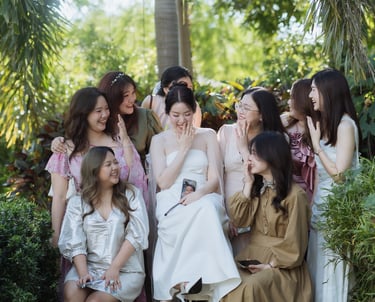 เจ้าสาวในชุดแต่งงานสีขาวถ่ายภาพกับแก๊งเพื่อนสาวกลางสวน บรรยากาศงานแต่งโทนอบอุ่น โดยช่างภาพงานแต่งน่า