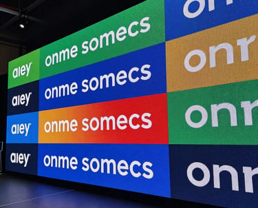 A wide shot of a multi-screen LED video wall display at a corporate launch event in a North American venue, vibrant colors and sharp text.