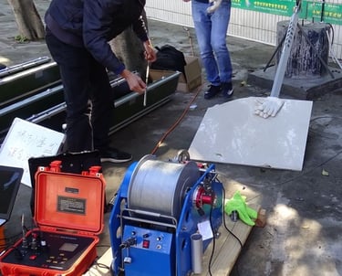 Industrial borewell inspection camera equipment with a motorized cable winch and control unit being operated outdoors.