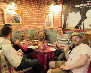 A group of friends enjoying dinner and drinks at a rustic restaurant with red brick walls.