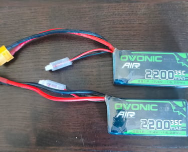 Duas baterias recarregáveis para carros RC com conectores e fios visíveis