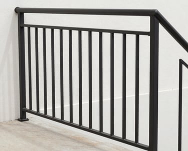 A welder focused on detailed railing fabrication, sparks flying gently in a workshop setting.