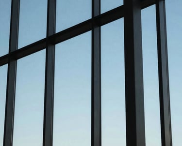An abstract, professional shot of modern office windows reflecting a blue sky. The composition is clean and geometric, representing precision.